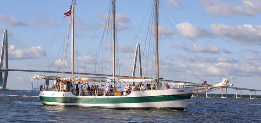 Guests enjoy a sail in Charleston Harbor with the Ravenel Bridge in the background.