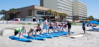 A bachelor party group gets land instruction before their time surfing in the water.